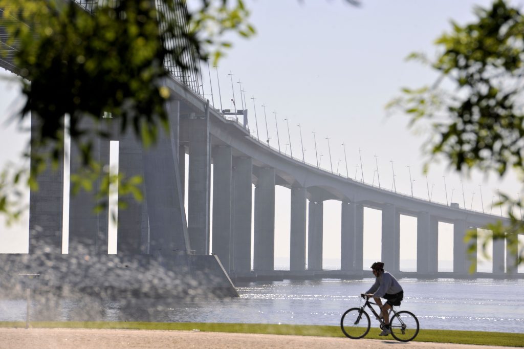 Man riding bicycle past Tagus Bridges